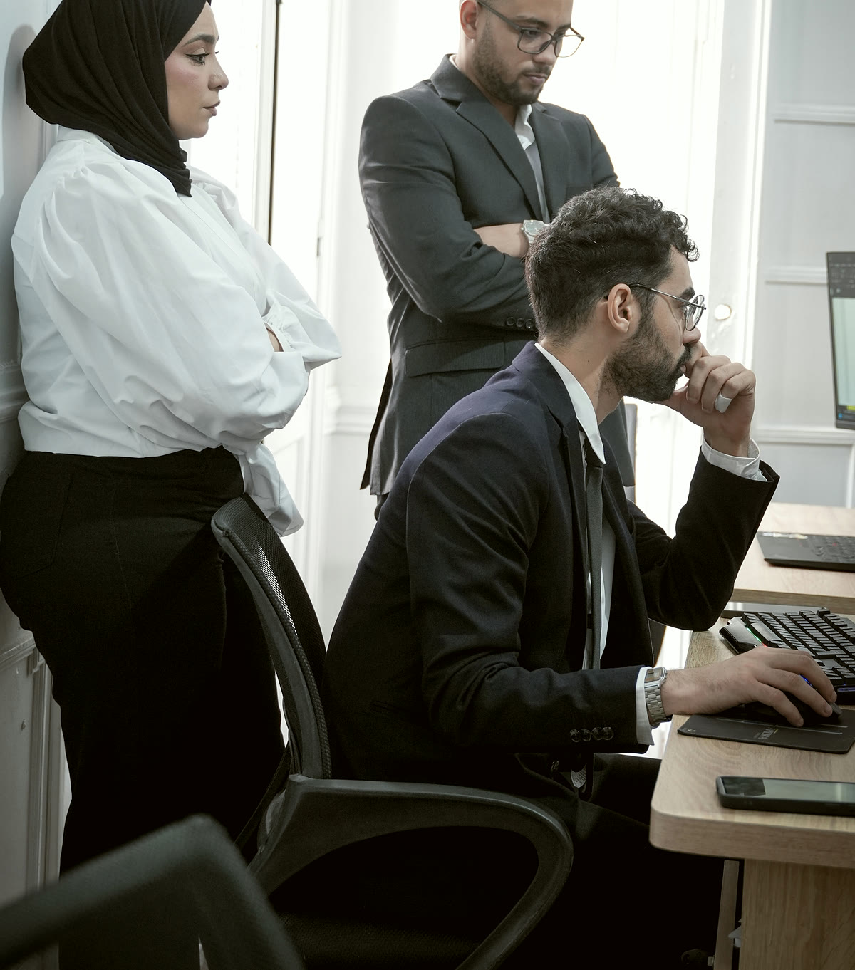 Trois membres de l’équipe examinent un dossier à un poste de travail.